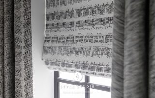 Patterned roman blinds behind curtains